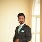 Portrait of a man in a pinstripe suit with a turquoise tie, indoors.